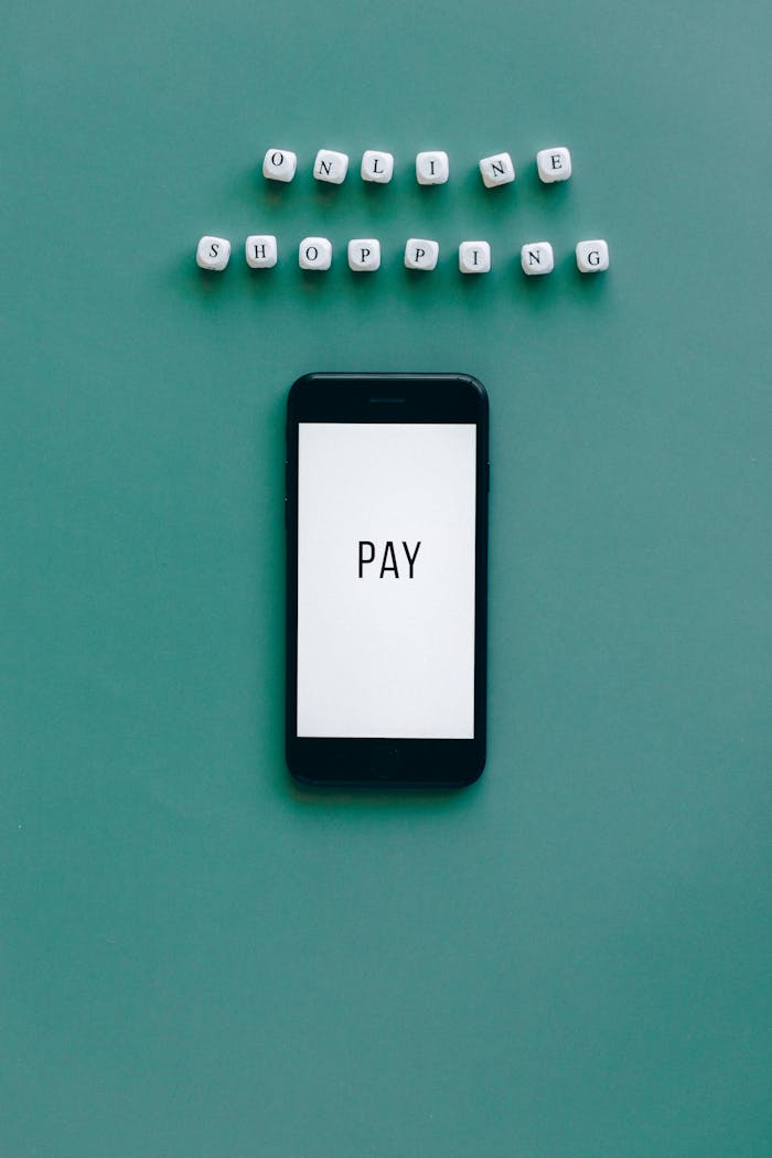 Smartphone displaying Pay with letter blocks spelling Online Shopping on a green background. Perfect for e-commerce themes.